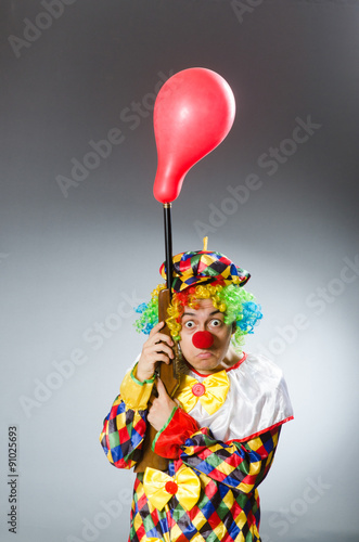 Clown with balloon and rifle in funny concept