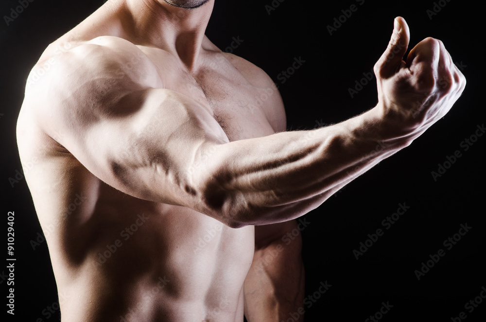 Muscular man posing in dark studio Muscular man posing in dark studio