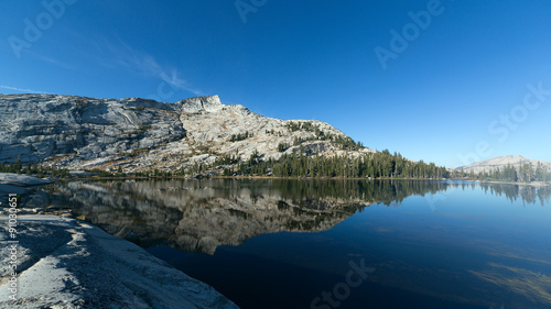 Mountain and pine trees reflecting on alpine lake photo