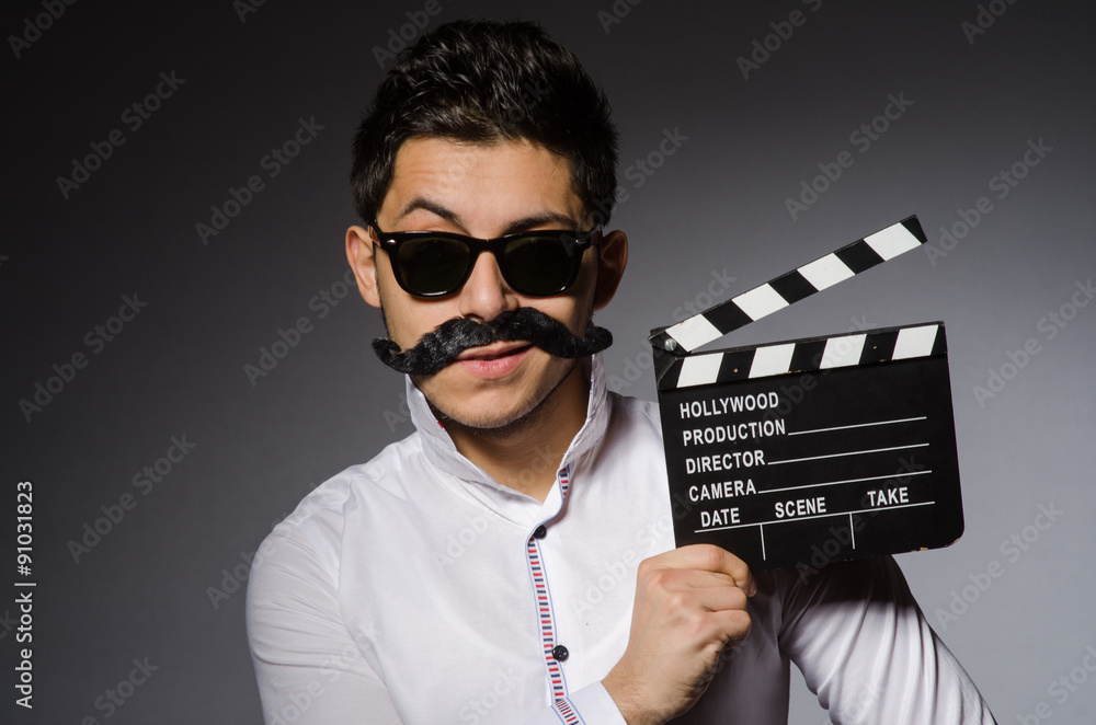 Young caucasian man with clapperboard against gray Young caucasian man with clapperboard against gray