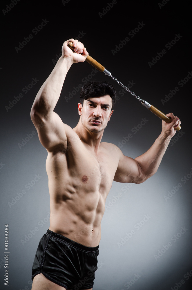 Muscular strong man with nunchucks Muscular strong man with nunchucks