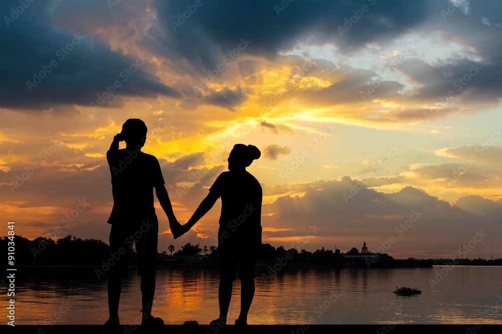 Fototapeta premium Silhouette of couple beside the river with beautiful sunset
