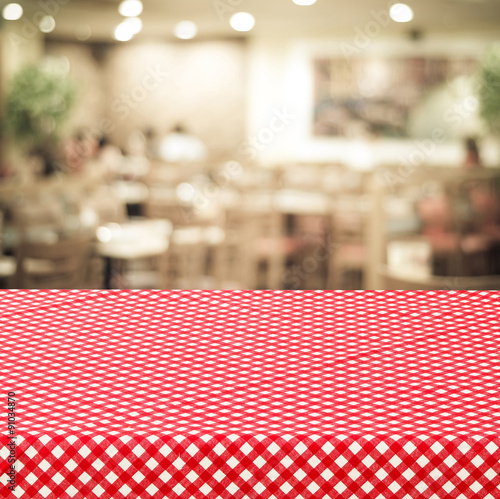 Empty table with red check table cloth over blurred cafe