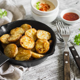 baked potatoes in the pan on a light wooden surface
