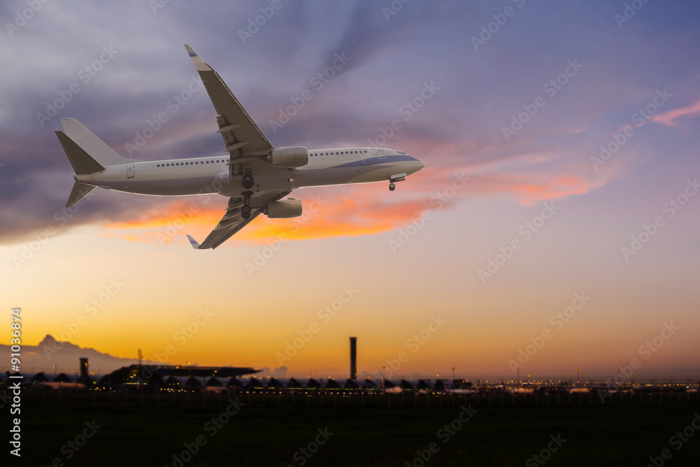 Commercial airplane flying over the airport at sunset