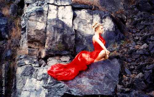 девушка в красном платье , на камнях занимается йогой