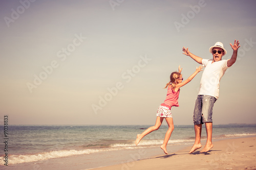 Father and daughter playing on the beach at the day time.