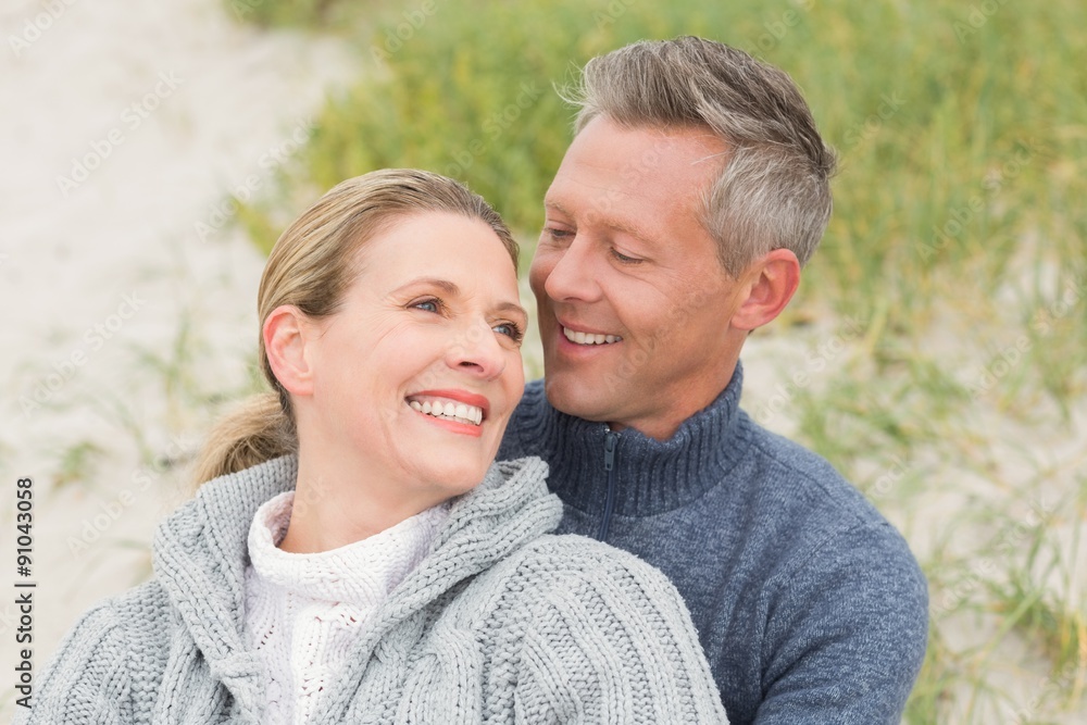 Fototapeta premium Smiling couple sitting on the sand