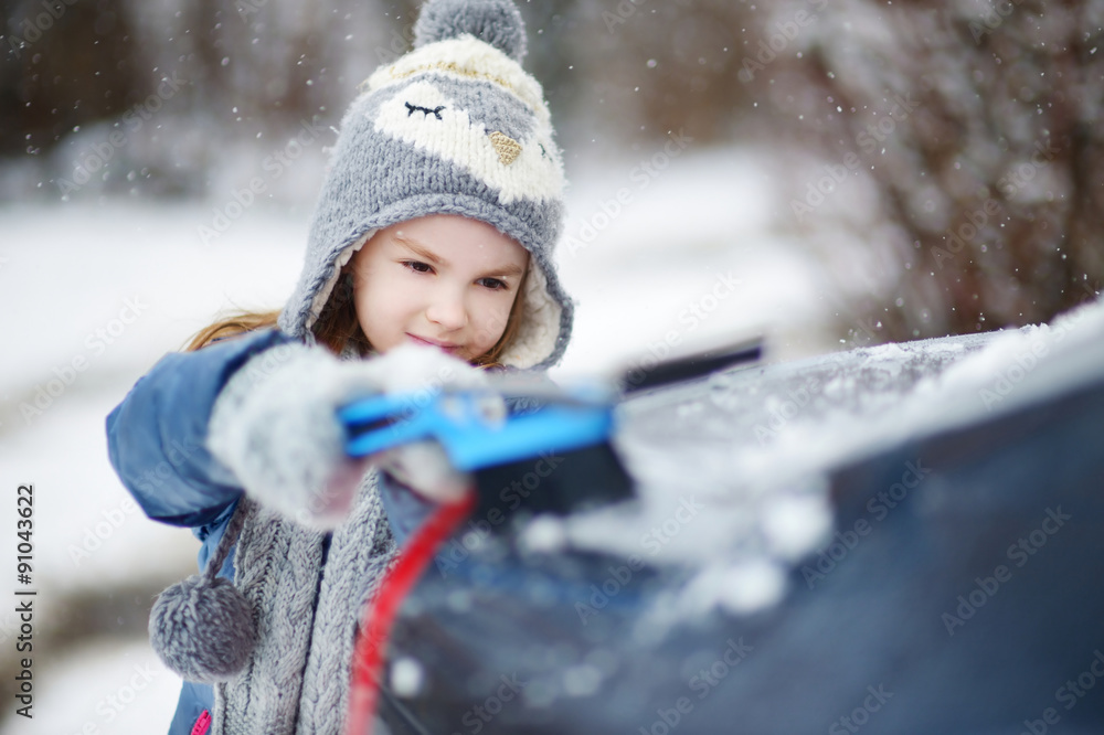 Adorable little girl helping to brush a snow Adorable little girl helping to brush a snow