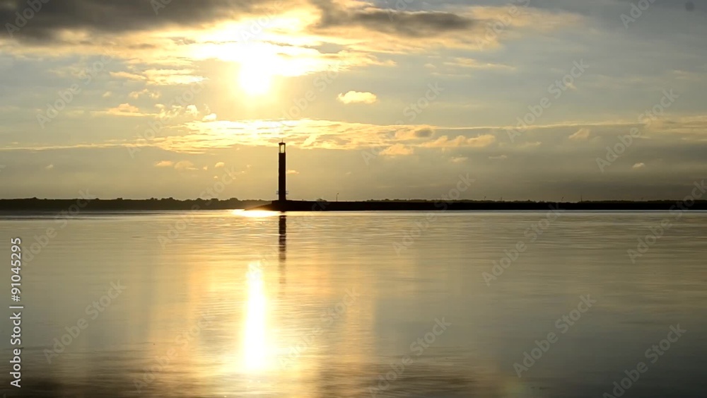 Time lapse of water landscape with lighthouse and clouds at dawn Time lapse of water landscape with lighthouse and clouds at dawn