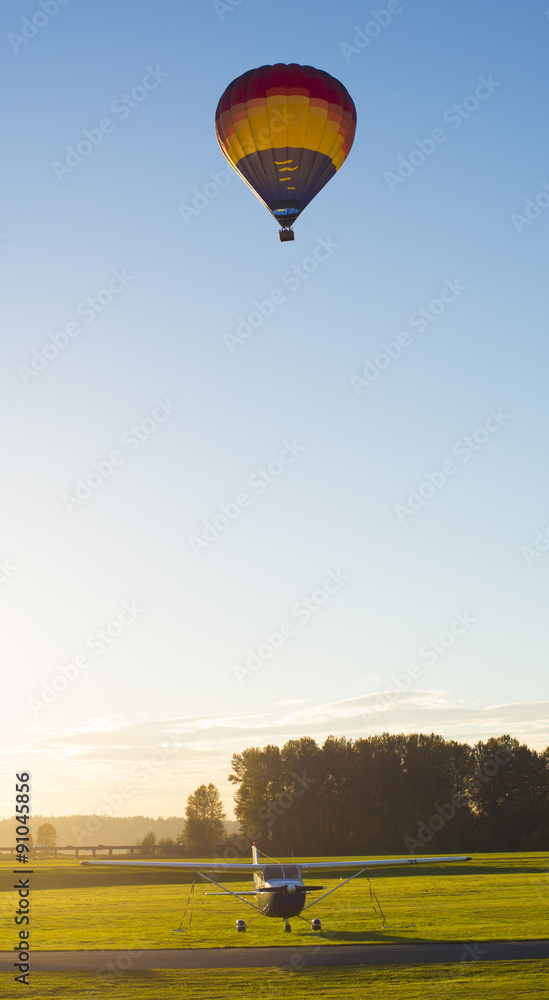 Obraz premium Hot Air Balloon and Plane at an airport