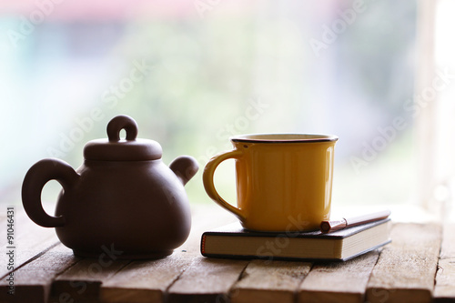 vintage old teapot clay cup and notebook on wooden table
