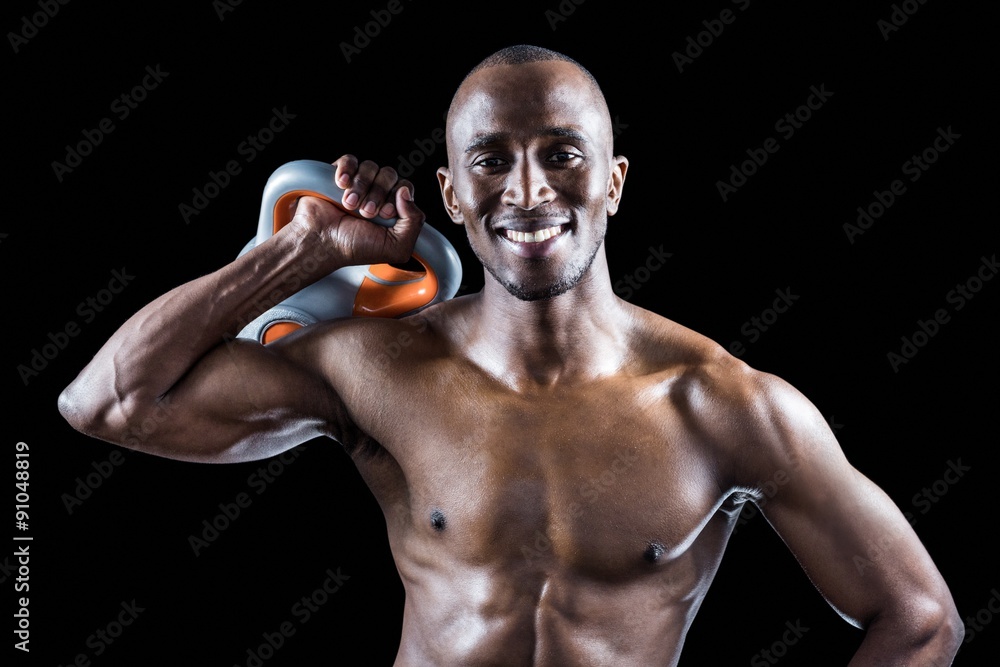 Portrait of muscular man smiling while holding kettlebell