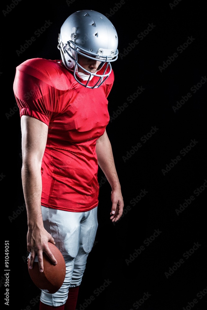 American football player with ball looking down American football player with ball looking down
