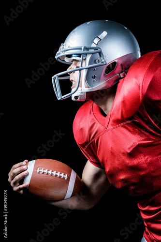 Side view of aggressive sportsman playing American football
