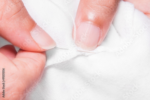 women s hands while sewing white cloth