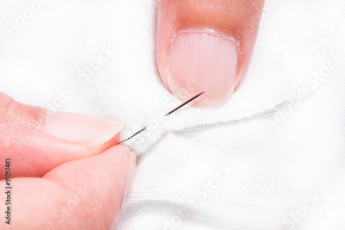women's hands while sewing white cloth