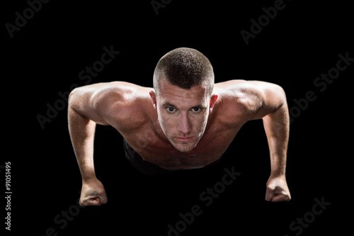 Portrait of confident shirtless man doing push ups