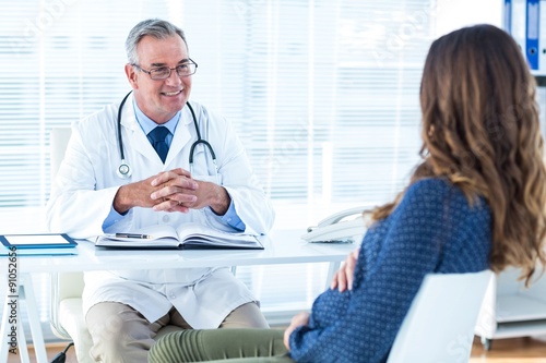 Male doctor discussing with pregnant woman in clinic