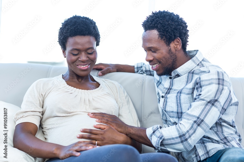Happy man with pregnant wife touching her belly at home Happy man with pregnant wife touching her belly at home