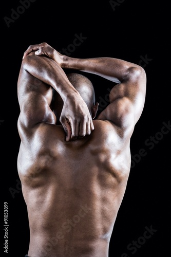 Rear view of muscular athlete stretching