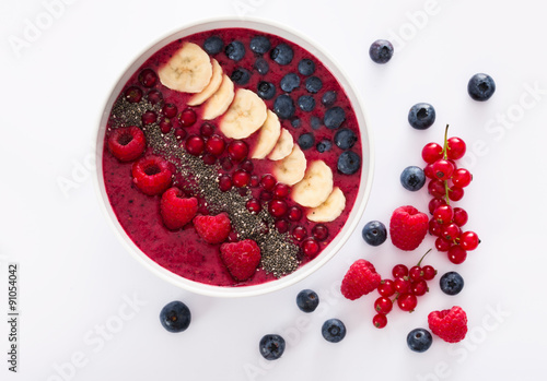 berry smoothie bowl with chia seeds, bananas, blueberries, currant and raspberries on white background 