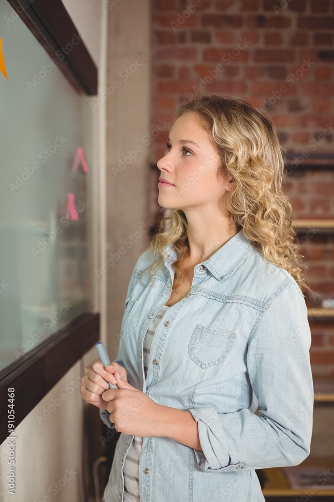 Businesswoman holding marker in creative office