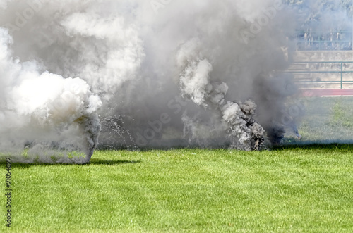Background of fumes. Two smoke bombs launched over the grass, during an army show.