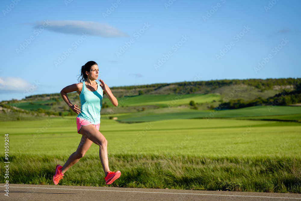 Sporty woman running fast on country side road. Female athlete training outdoor. Sporty woman running fast on country side road. Female athlete training outdoor.