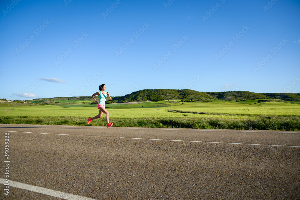 Sporty woman running on country side road. Female athlete training and exercising outdoor.