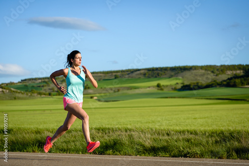 Sporty woman running fast on country side road. Female athlete training outdoor.