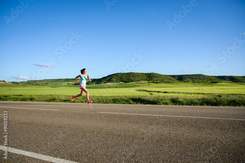 Sporty woman running on country side road. Female athlete training and exercising outdoor.