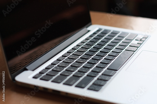 open laptop with black screen on modern wooden desk