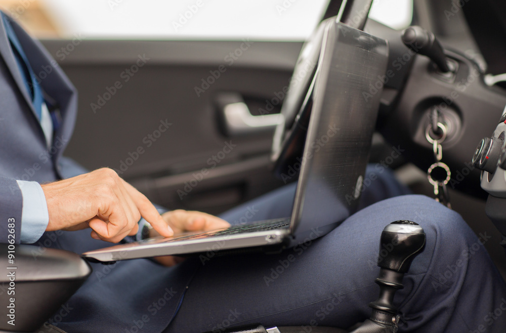 close up of young man with laptop driving car