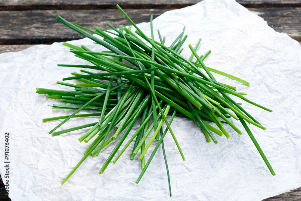 Fresh Green Vegetables Bunch of Chives on crumpled paper and old wooden table. Fresh Green Vegetables Bunch of Chives on crumpled paper and old wooden table.