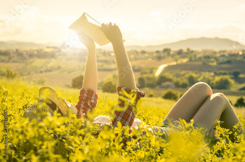 girl reading a book lying on the grass - people, nature, hobby and lifestyle concept