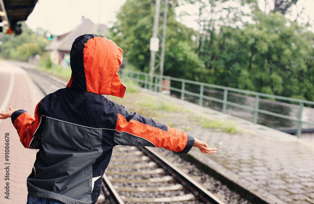 7 years old boy standing on a railway station and waiting for th 7 years old boy standing on a railway station and waiting for th