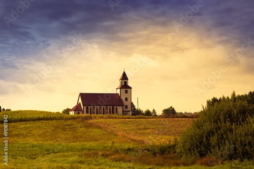 Countryside panorama with picturesque village church by the corn field. Sedki, Poland.