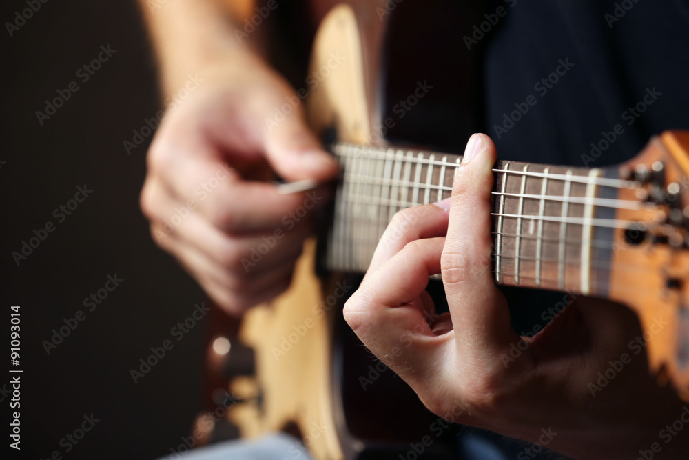 Young musician playing acoustic guitar close up