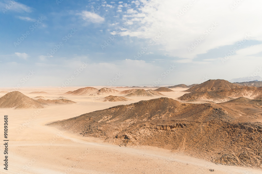 Beautiful desert landscape of Egypt. Yellow sand, mountains, clouds and blue sky.