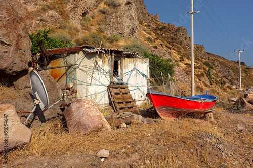 Little hut and a red boat in front of rocky hill photo