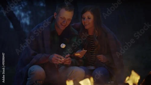 Medium panning slow motion shot of couple toasting marshmallows / American Fork Canyon, Utah, United States photo