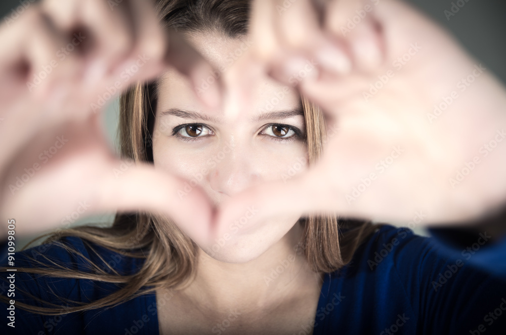 Fototapeta premium closeup portrait of cute young teen girl making a heart with