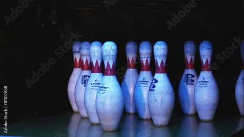 bowling pins being knocked down by a bowling ball in a bowling alley