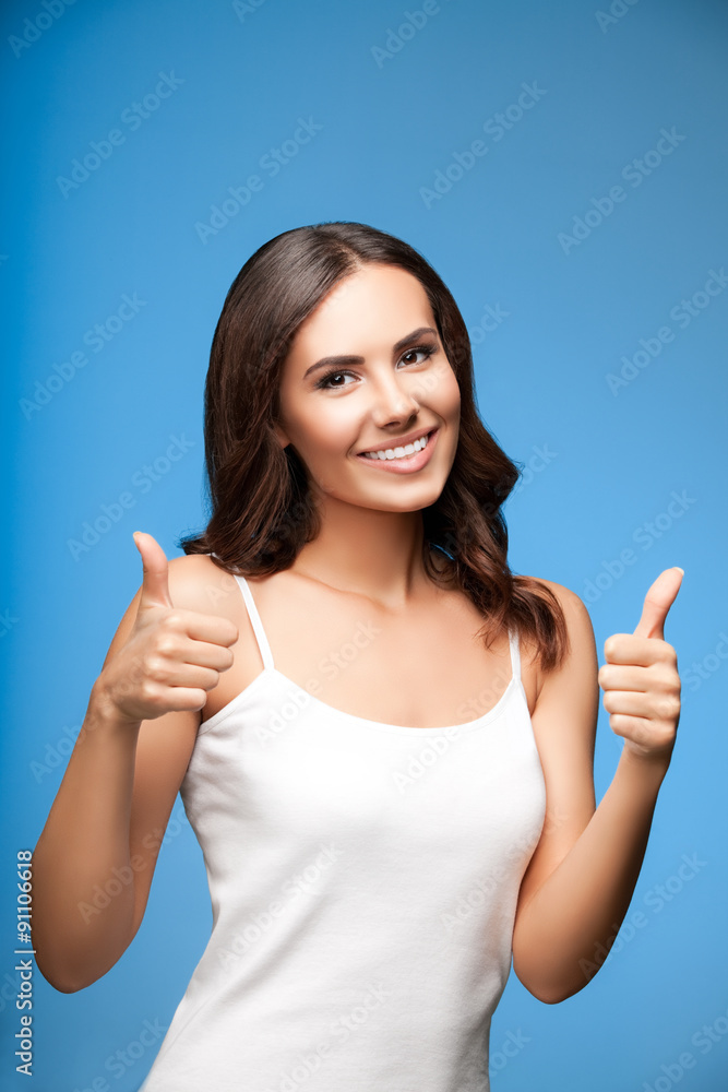 young woman showing thumb up gesture, on blue young woman showing thumb up gesture, on blue