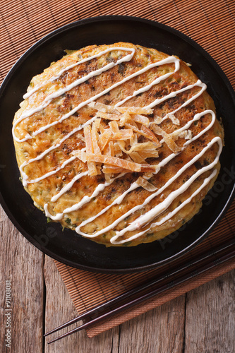 Japanese okonomiyaki on a table close-up. vertical top view
 photo