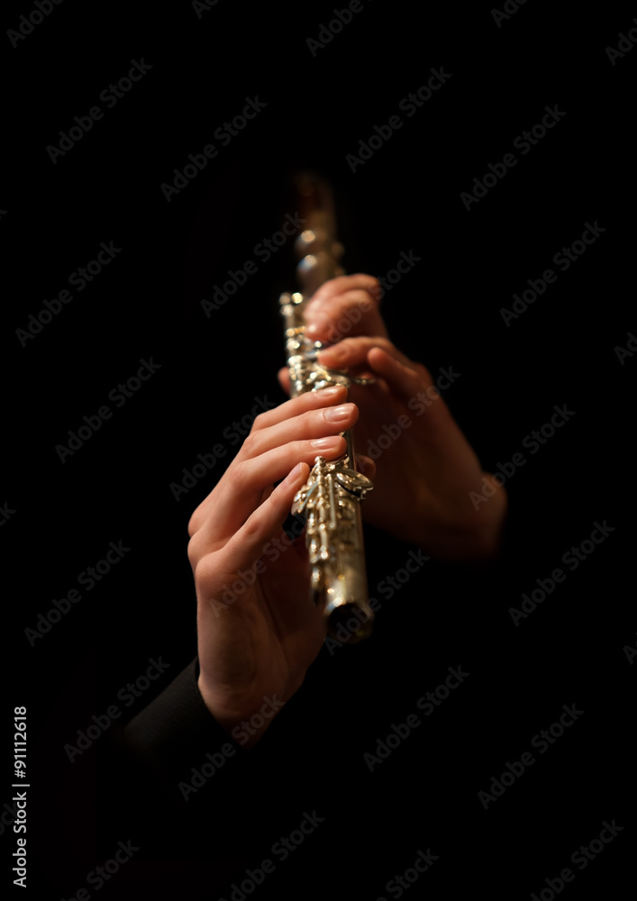 Fototapeta premium Hands of man playing a flute on a black background