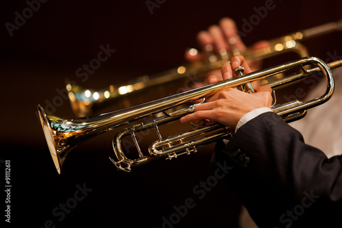 Hands of man playing the trumpet in the orchestra in dark colors