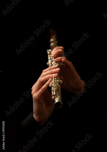 Hands of man playing a flute on a black background