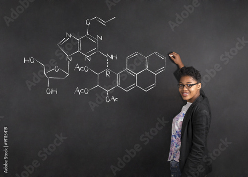 African American woman teacher writing science on chalk black board background photo